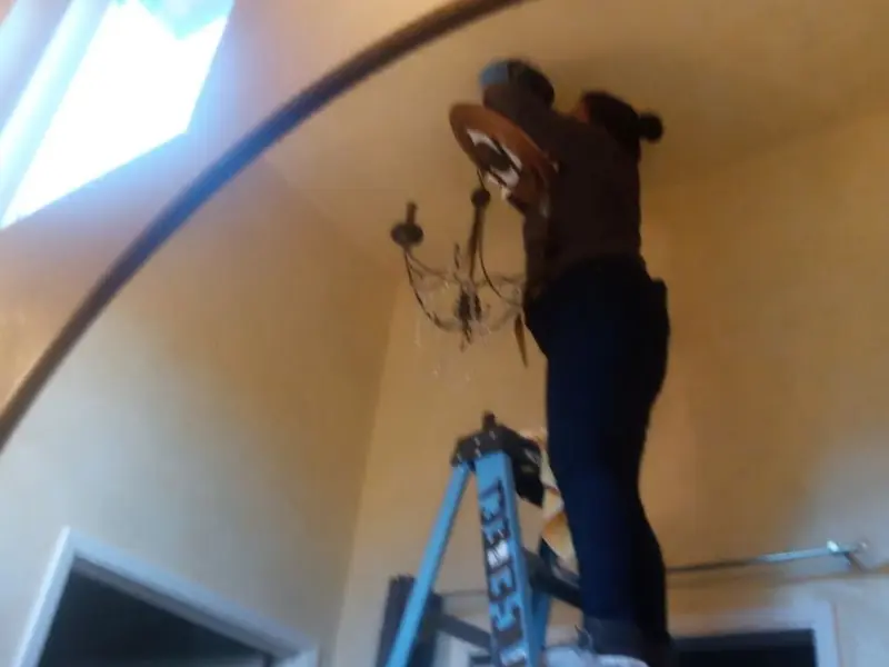 Electrician installing a chandelier in a Corning residence